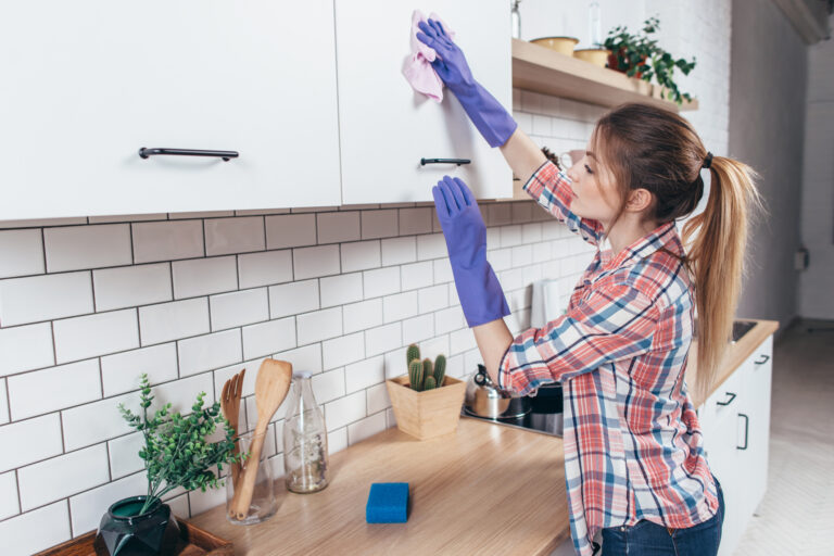 Young woman cleaning the furniture in the kitchen.